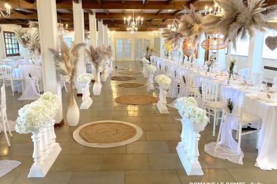 Table élégamment dressée avec vaisselle blanche et décorations florales, donnant sur une piste équestre en arrière-plan.