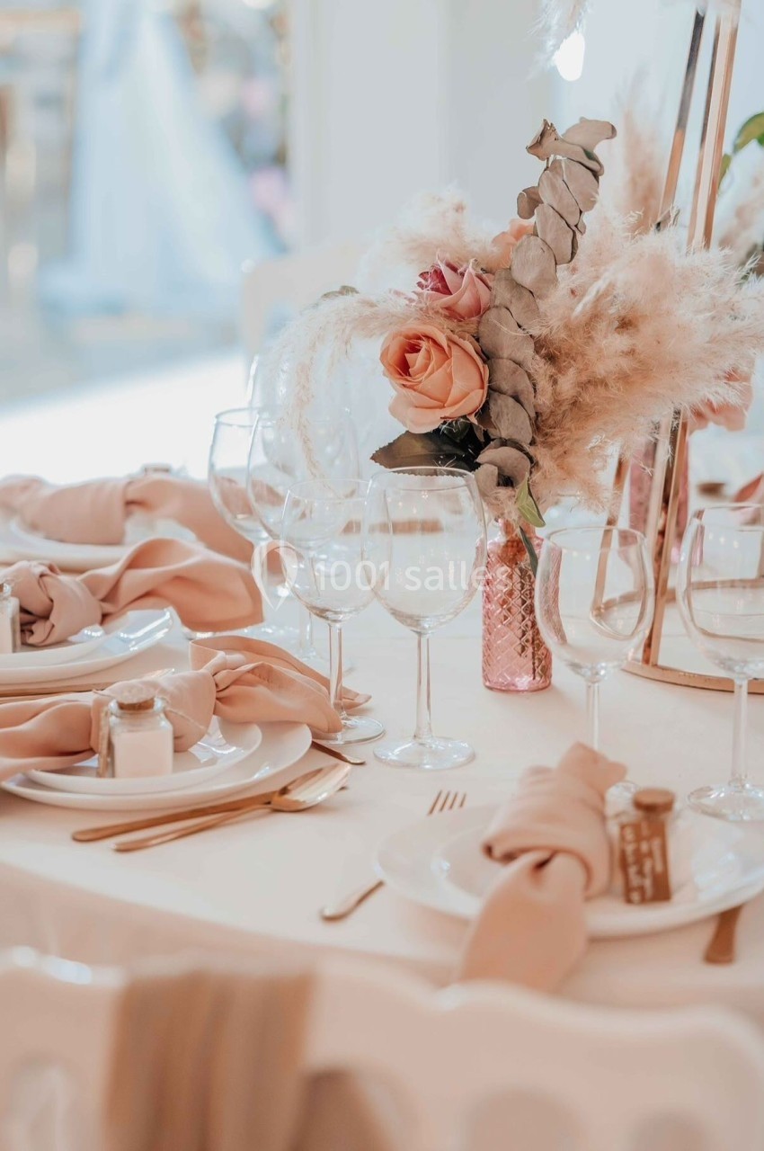 DOMAINE LE COMTE - jusque 200 personnes Table élégamment dressée avec vaisselle blanche, serviettes beige rosé et centre de table floral avec pampas et roses.