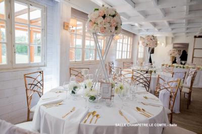 Table élégamment dressée avec vaisselle blanche et décorations florales, donnant sur une piste équestre en arrière-plan.