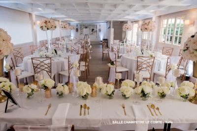 Table élégamment dressée avec vaisselle blanche et décorations florales, donnant sur une piste équestre en arrière-plan.