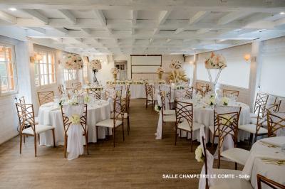 Table élégamment dressée avec vaisselle blanche et décorations florales, donnant sur une piste équestre en arrière-plan.