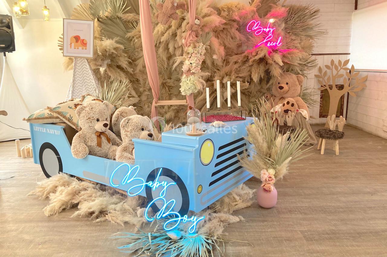 Décoration de fête avec un thème enfantin, comprenant un camion bleu, des peluches et des éléments végétaux.