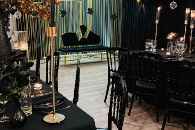 Miniature SALLE CHAMPETRE - jusque 100 pers Salle de réception élégante avec décoration noire et dorée, tables dressées et bougies allumées.