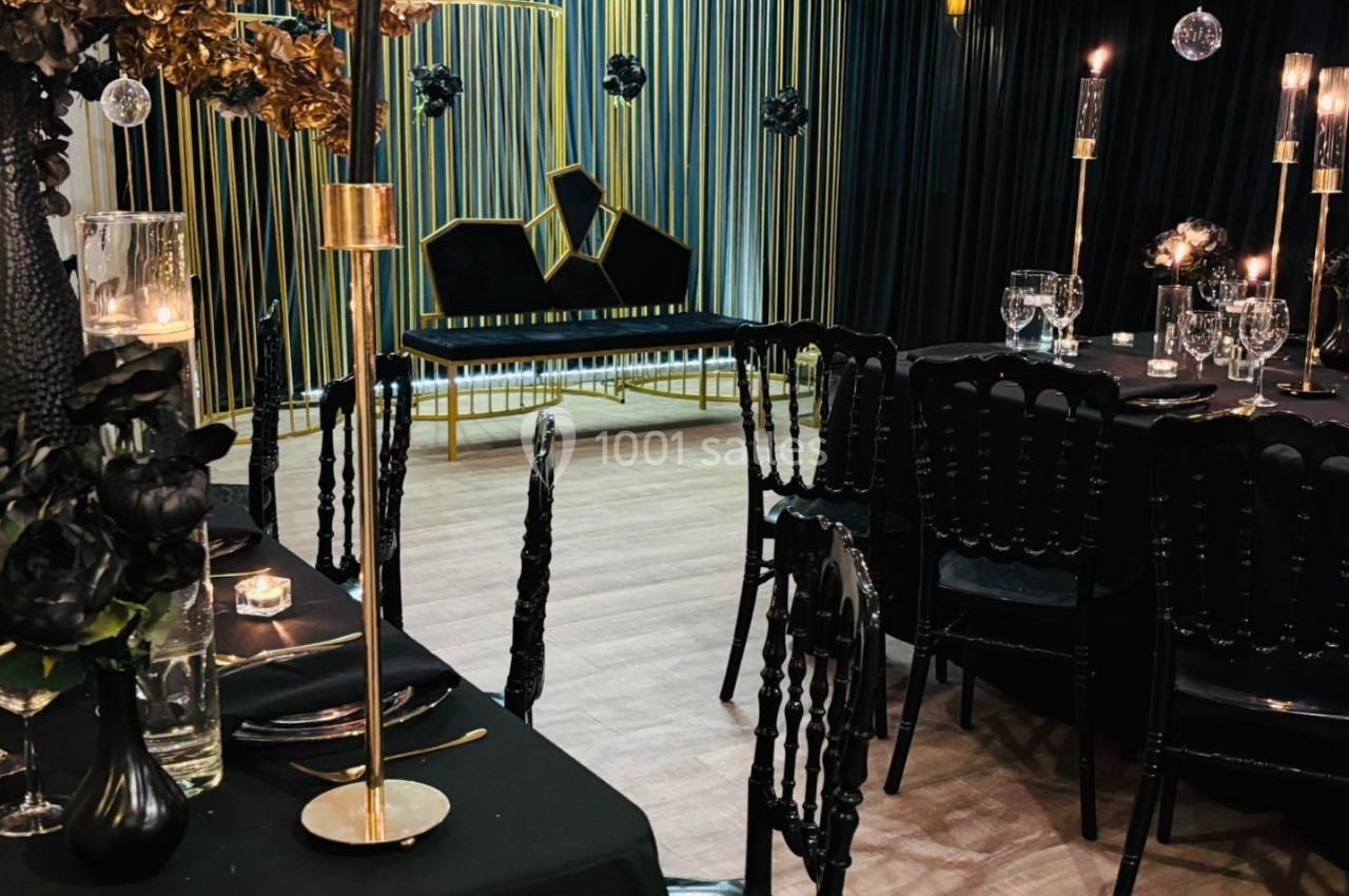 SALLE CHAMPETRE - jusque 100 pers Salle de réception élégante avec décoration noire et dorée, tables dressées et bougies allumées.