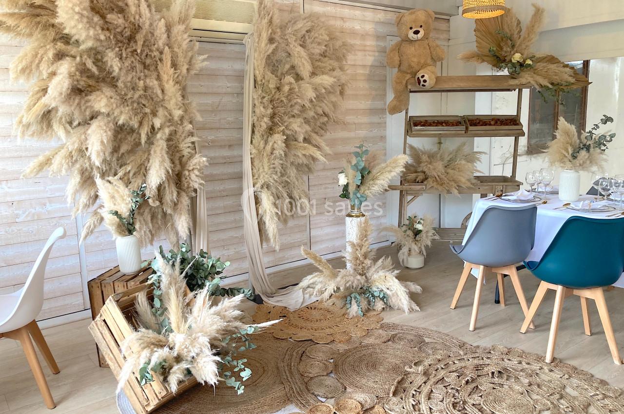 SALLE COSY - 80 PERS - Location à la journée 8h-18h Décoration intérieure avec pampas, tapis en fibres naturelles, chaises modernes et table dressée dans un style bohème.