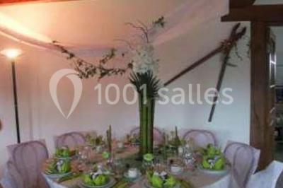 Lit double avec couvre-lit blanc, deux oreillers, table de chevet avec lampe rose et décoration florale sur les murs.