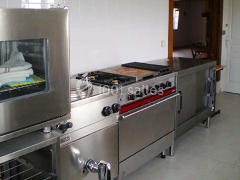 Cuisine professionnelle équipée d'un four, d'une cuisinière à gaz et de plans de travail en inox.