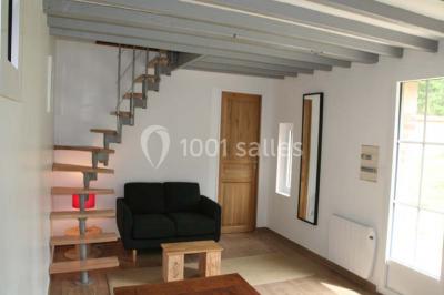 Deux canapés gris dans un salon lumineux avec une grande fenêtre, une lampe allumée et des décorations murales.