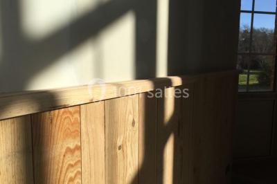 Deux canapés gris dans un salon lumineux avec une grande fenêtre, une lampe allumée et des décorations murales.