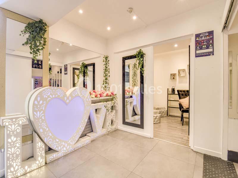 Décoration intérieure avec lettres lumineuses ’LOVE’, miroir, fleurs et plantes suspendues dans un espace lumineux.