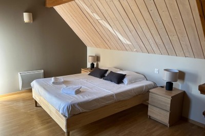 Terrasse en bois avec mobilier de jardin, offrant une vue dégagée sur un paysage verdoyant et boisé.