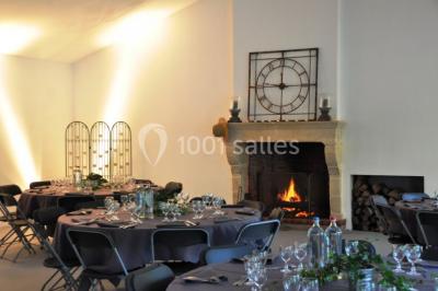 Salle de réunion lumineuse sous combles avec poutres apparentes, tables, chaises et écran de projection installé.