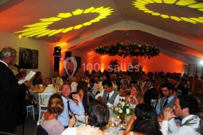 Salle de réunion lumineuse sous combles avec poutres apparentes, tables, chaises et écran de projection installé.