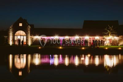 Salle de réunion lumineuse sous combles avec poutres apparentes, tables, chaises et écran de projection installé.