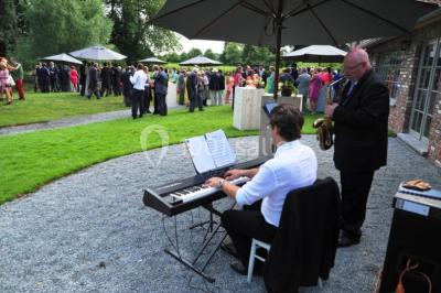 Salle de réunion lumineuse sous combles avec poutres apparentes, tables, chaises et écran de projection installé.