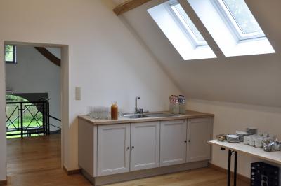 Salle de réunion lumineuse sous combles avec poutres apparentes, tables, chaises et écran de projection installé.