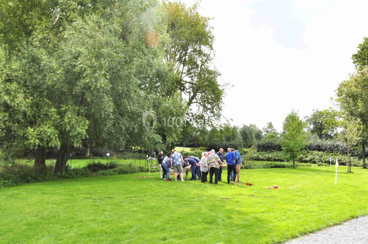 Un groupe de personnes rassemblées sur une pelouse verte dans un parc, entouré d'arbres et de végétation.