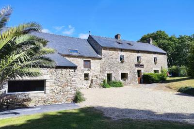 Chemin en pierre menant à une petite maison en bois entourée de végétation dense et ombragée.