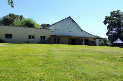 Chemin en pierre menant à une petite maison en bois entourée de végétation dense et ombragée.