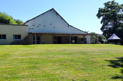 Chemin en pierre menant à une petite maison en bois entourée de végétation dense et ombragée.