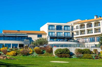 Salle de restaurant moderne avec une grande table en bois, suspensions noires et étagères de bouteilles illuminées.