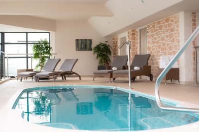Salle de restaurant moderne avec une grande table en bois, suspensions noires et étagères de bouteilles illuminées.