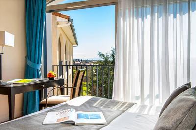 Salle de restaurant moderne avec une grande table en bois, suspensions noires et étagères de bouteilles illuminées.