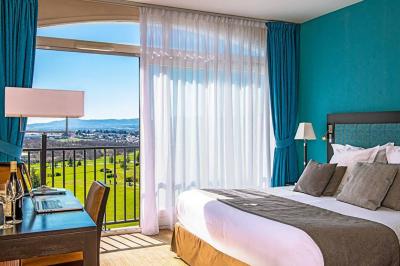 Salle de restaurant moderne avec une grande table en bois, suspensions noires et étagères de bouteilles illuminées.