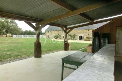 Salle de bain avec lavabo, miroir, toilettes et porte-serviettes, carrelage sombre au sol et murs clairs.