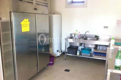 Salle de bain avec lavabo, miroir, toilettes et porte-serviettes, carrelage sombre au sol et murs clairs.