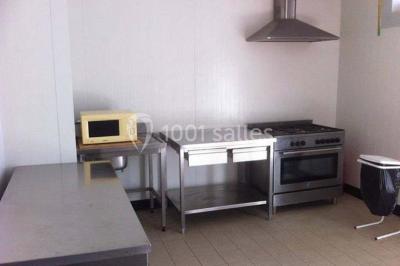 Salle de bain avec lavabo, miroir, toilettes et porte-serviettes, carrelage sombre au sol et murs clairs.