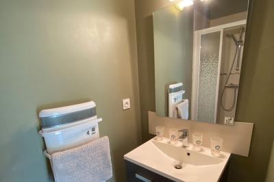 Salle de bain avec lavabo, miroir, toilettes et porte-serviettes, carrelage sombre au sol et murs clairs.