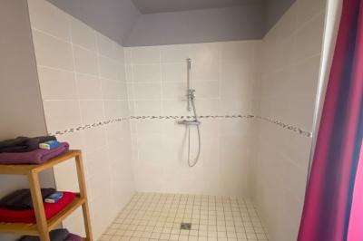 Salle de bain avec lavabo, miroir, toilettes et porte-serviettes, carrelage sombre au sol et murs clairs.