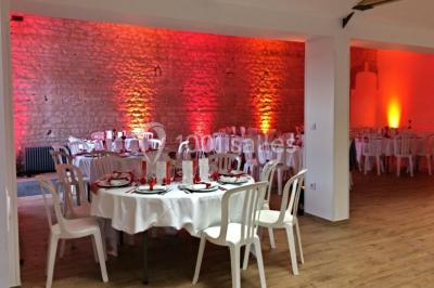 Dortoir avec lits superposés en métal noir, murs rouges et blancs, sol en carrelage foncé, éclairage au plafond.