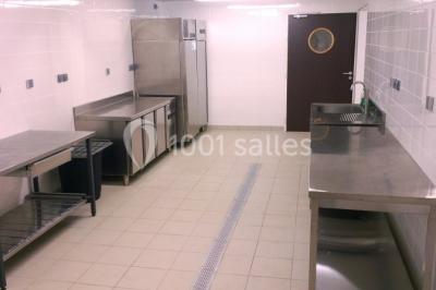 Dortoir avec lits superposés en métal noir, murs rouges et blancs, sol en carrelage foncé, éclairage au plafond.