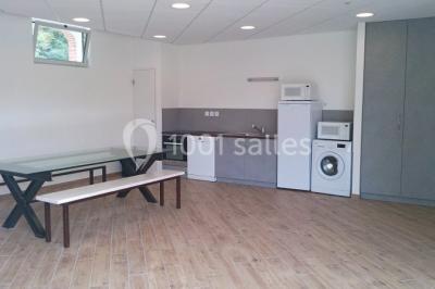 Dortoir avec lits superposés en métal noir, murs rouges et blancs, sol en carrelage foncé, éclairage au plafond.