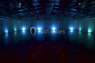 Dortoir avec lits superposés en métal noir, murs rouges et blancs, sol en carrelage foncé, éclairage au plafond.