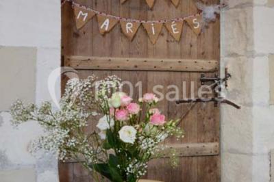 Couronne décorative suspendue sous un plafond en bois, ornée de feuillages, fleurs séchées et éléments naturels.