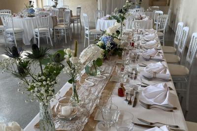 Couronne décorative suspendue sous un plafond en bois, ornée de feuillages, fleurs séchées et éléments naturels.