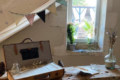 Couronne décorative suspendue sous un plafond en bois, ornée de feuillages, fleurs séchées et éléments naturels.