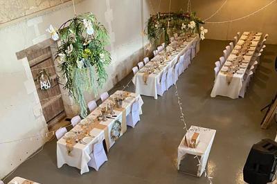 Couronne décorative suspendue sous un plafond en bois, ornée de feuillages, fleurs séchées et éléments naturels.