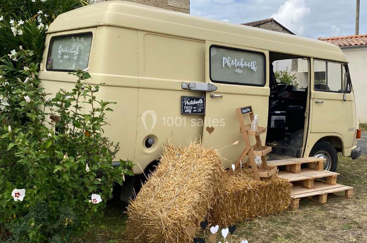 Fourgon vintage beige aménagé en photobooth, entouré de bottes de paille, fleurs et petites marches en bois.