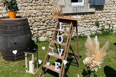 Couronne décorative suspendue sous un plafond en bois, ornée de feuillages, fleurs séchées et éléments naturels.