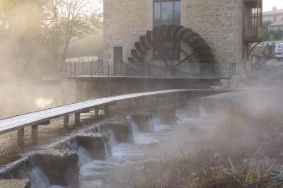 Vélo ancien garé devant une structure en bois et métal avec des toiles blanches tendues, entourée de verdure.