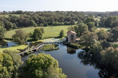 Vélo ancien garé devant une structure en bois et métal avec des toiles blanches tendues, entourée de verdure.