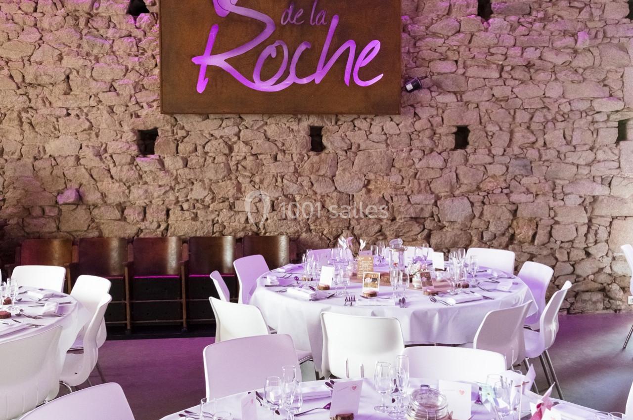 Salle de réception avec murs en pierre, tables dressées et un panneau lumineux indiquant ’La Vallée de la Roche’.