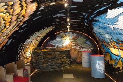 Vélo ancien garé devant une structure en bois et métal avec des toiles blanches tendues, entourée de verdure.