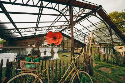 Vélo ancien garé devant une structure en bois et métal avec des toiles blanches tendues, entourée de verdure.