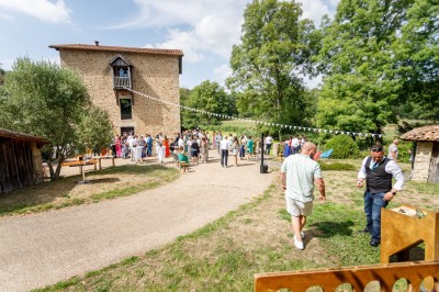 Ancien moulin en pierre avec une grande roue à aubes, bordé par un cours d'eau et entouré de végétation.
