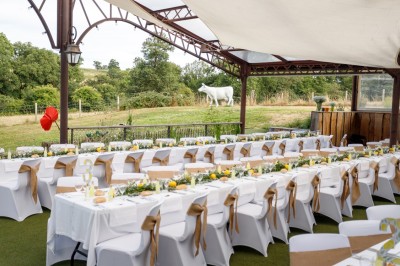 Ancien moulin en pierre avec une grande roue à aubes, bordé par un cours d'eau et entouré de végétation.